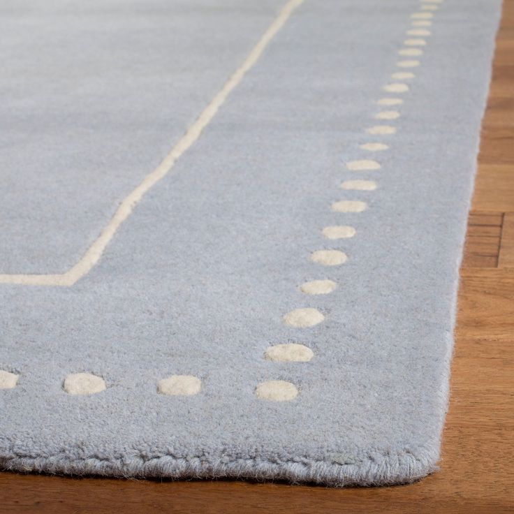 a light blue area rug with white dots on the top and bottom, laying on a wooden floor