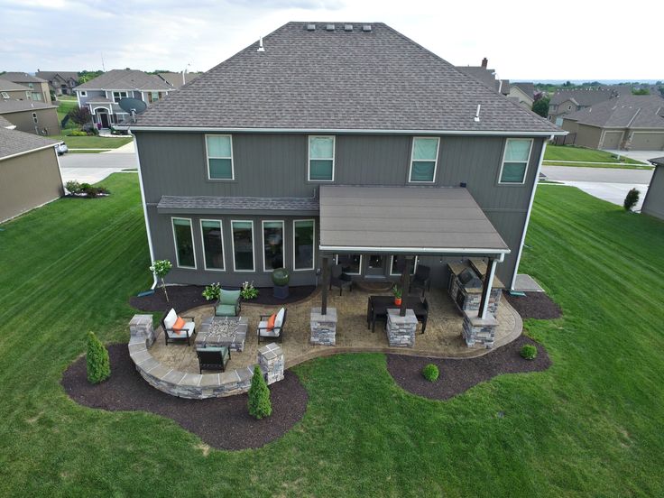 an aerial view of a house with patio furniture and outdoor living area in the foreground