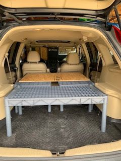 the back end of a car with an open trunk and two tables in front of it