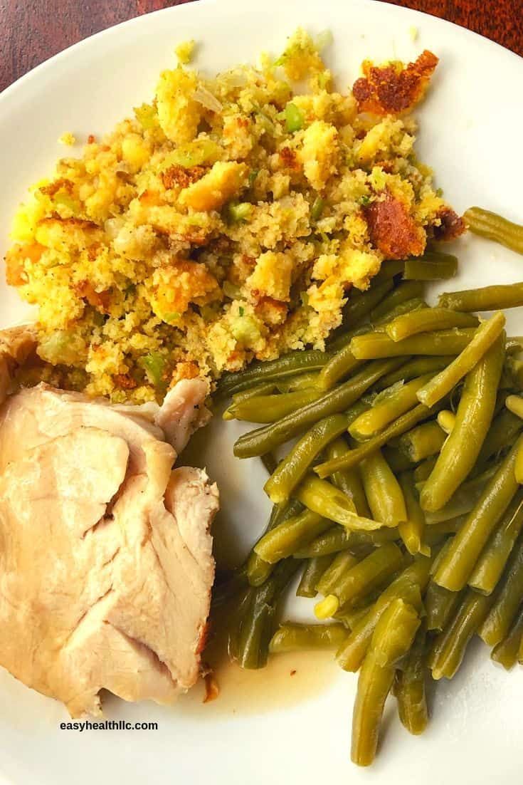 a white plate topped with green beans and meat next to stuffing on top of it