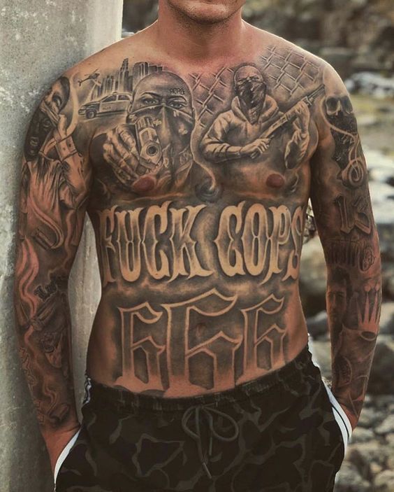 a man with tattoos on his chest standing next to a pillar