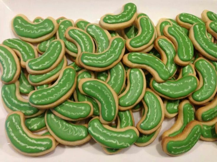 green and yellow decorated cookies are on a white platter, ready to be eaten