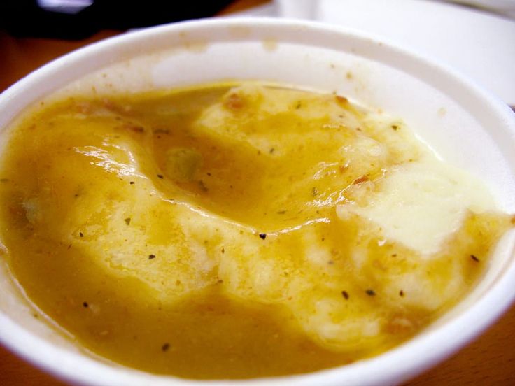 a white bowl filled with soup on top of a wooden table