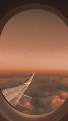 an airplane window looking out at the clouds and a crescente in the sky above