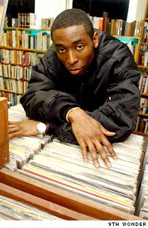 a man leaning on top of a stack of records in front of a bookshelf