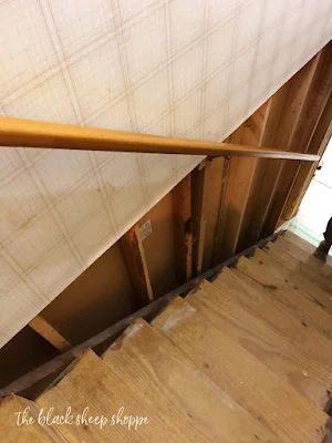 a wooden stair case with white sheets on it and a person standing in the doorway