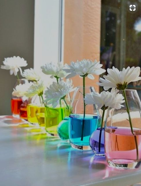 colorful vases with flowers in them sitting on a window sill