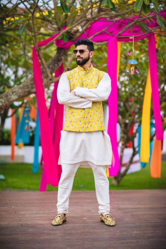 a man standing in front of colorful streamers with his arms crossed and looking at the camera