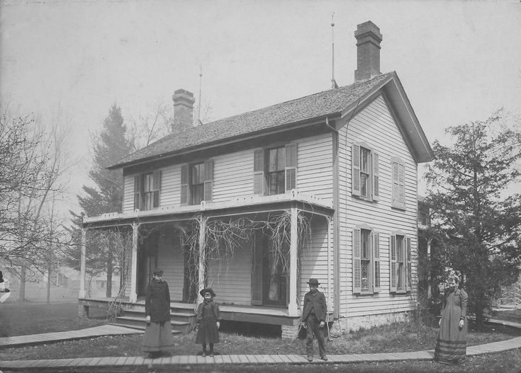 black and white photograph of an old brick building with stairs leading up to the second story