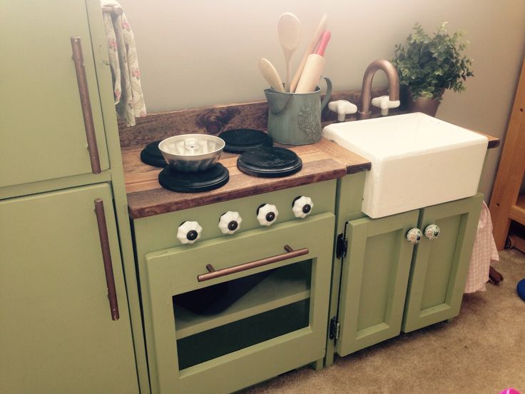 a kitchen with green cabinets and an old fashioned stove in the center is decorated with googly eyes