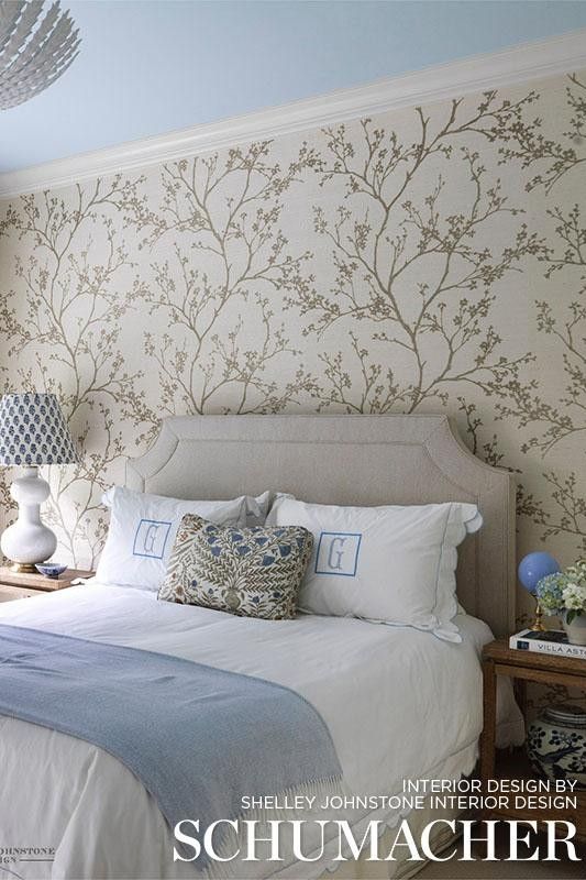 a bedroom with white bedding and wallpaper on the walls is featured in this magazine