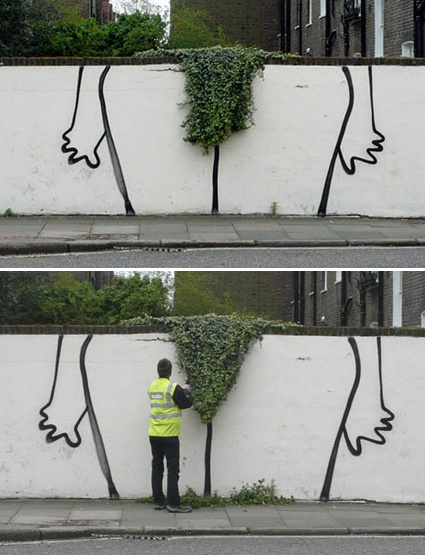 a man standing in front of a wall with a plant growing out of it's side