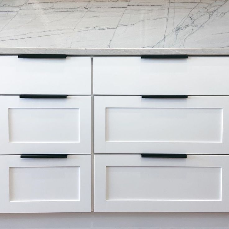 a white cabinet with black handles and drawers