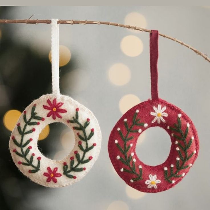 two ornaments hanging from a tree with lights in the background