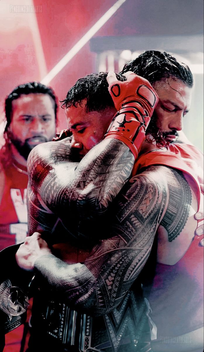 two men with tattoos on their arms hugging each other in front of a pink background