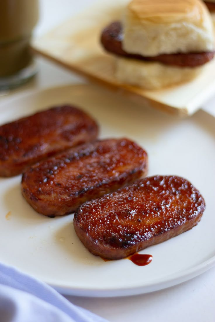 three sausages on a white plate next to a cup of coffee