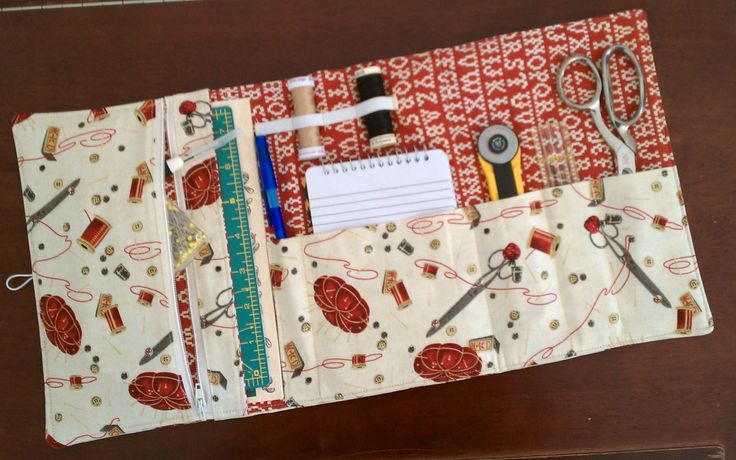 an open zippered pouch with scissors and sewing supplies in it on a wooden table