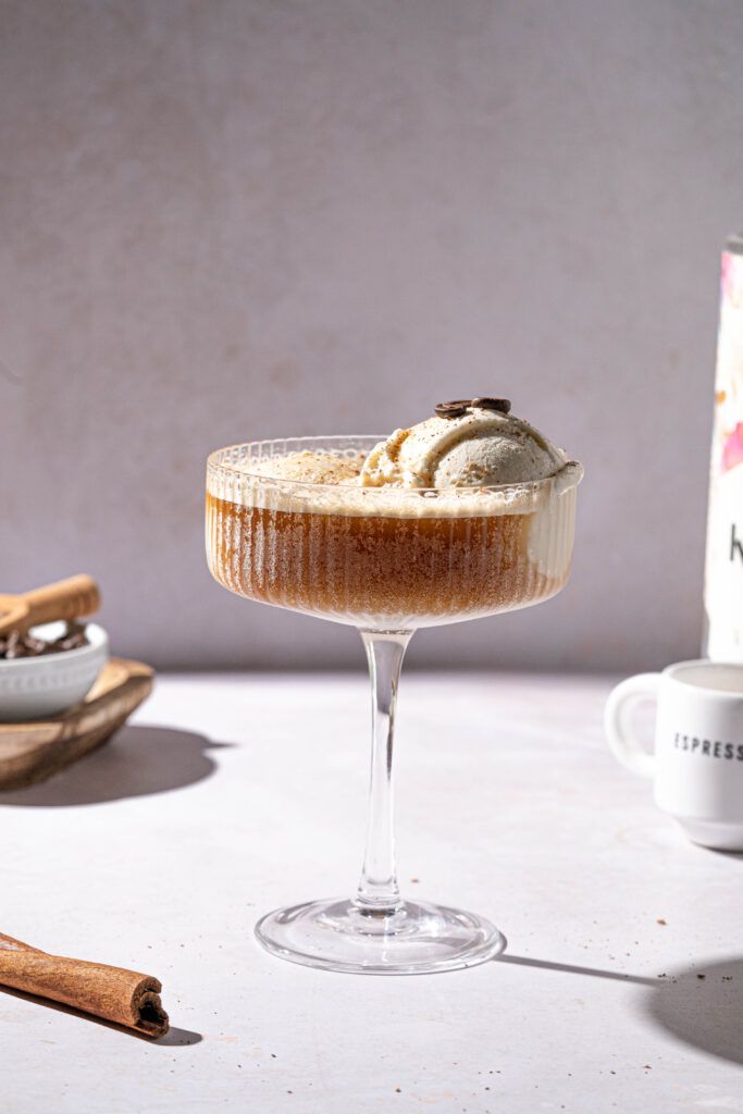 a dessert in a glass on a table next to cinnamon sticks and an empty cup