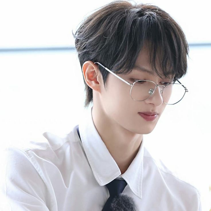 a young man wearing glasses and a tie holding chopsticks in his right hand