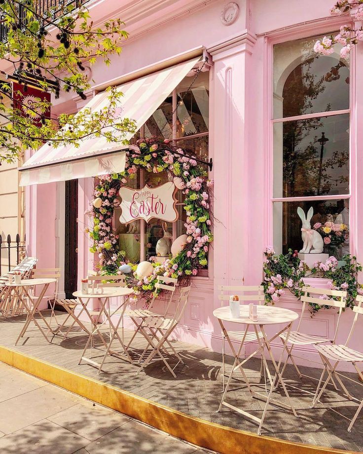 a pink store front with tables and chairs outside