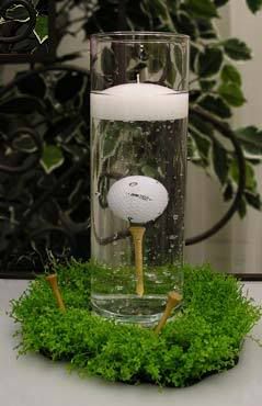 a golf ball is in a glass vase with water and moss on the table next to it