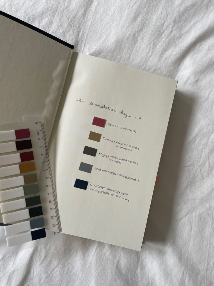 an open book with color swatches next to it on top of a white sheet