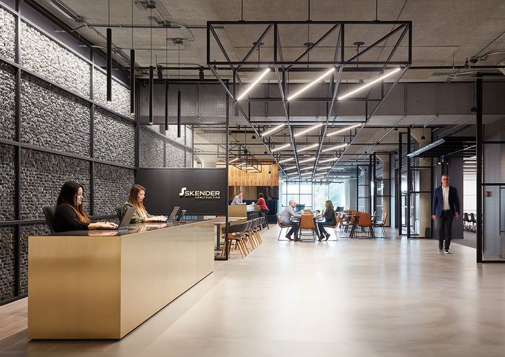 people are sitting at tables in an open office space with black and gold accents on the walls