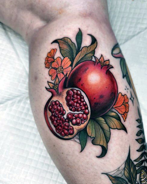 a pomegranate with leaves and flowers on the arm is shown in this tattoo design