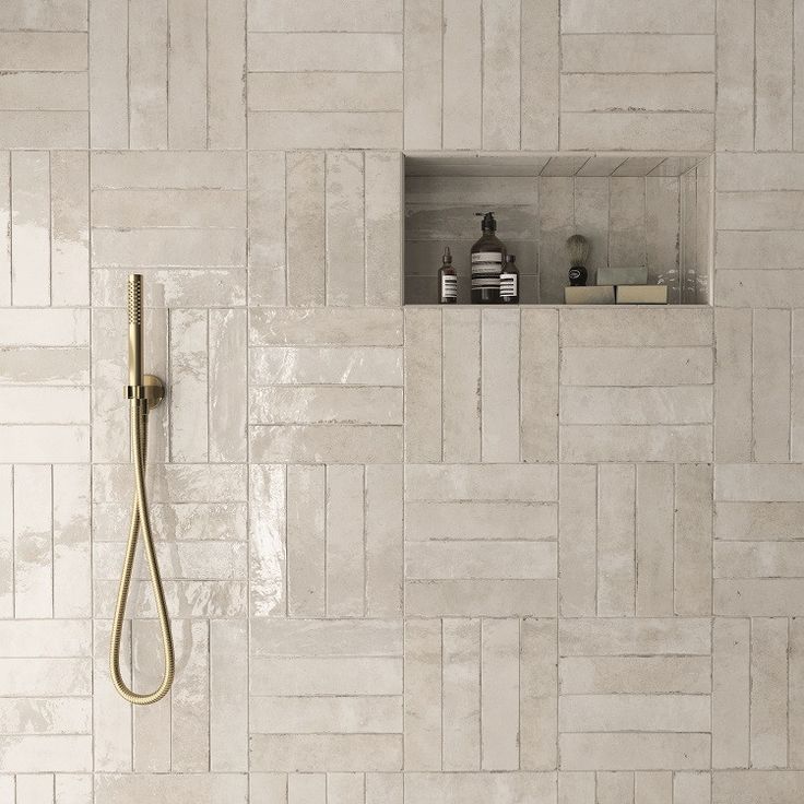 a white tiled bathroom with a shower head and hand held shower faucet in the corner