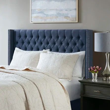 a blue headboard in a bedroom next to a night stand with flowers on it