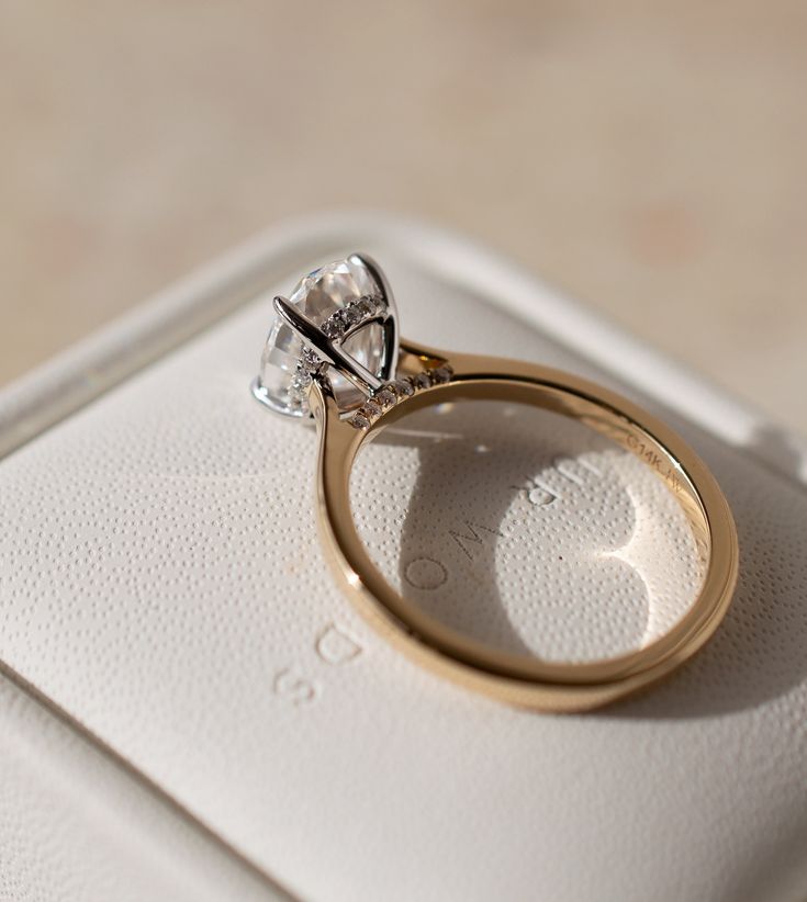 an engagement ring sitting on top of a white box with a diamond in the middle