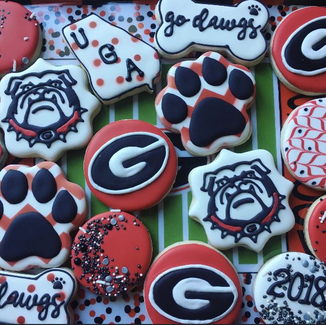 decorated cookies in the shape of dogs and footballs are displayed on a striped tablecloth