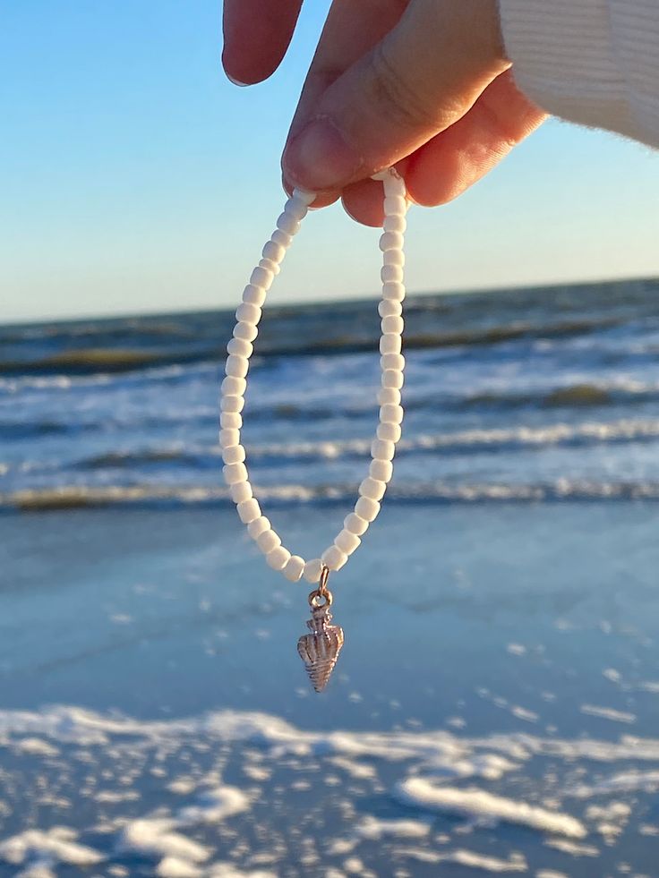 A white seed bracelet with a beautiful shiny seashell charm in the middle. Really cute and matches every outfit, perfect for kids and adults. Comes w/ 1 free sticker! Adjustable White Stretch Bracelet With Beachy Style, White Adjustable Stretch Bracelet With Beachy Style, White Stretch Bracelet With Pearl Charm And Round Beads, White Stretch Bracelet With Pearl Charm, Adjustable White Pearl Bracelet For Beach, Handmade White Pearl Bracelet For The Beach, Ocean-inspired White Bracelet As Gift, White Ocean-inspired Jewelry With Round Beads, Ocean-inspired White Bracelet Gift