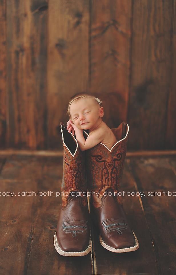 a newborn baby is curled up in a cowboy boot