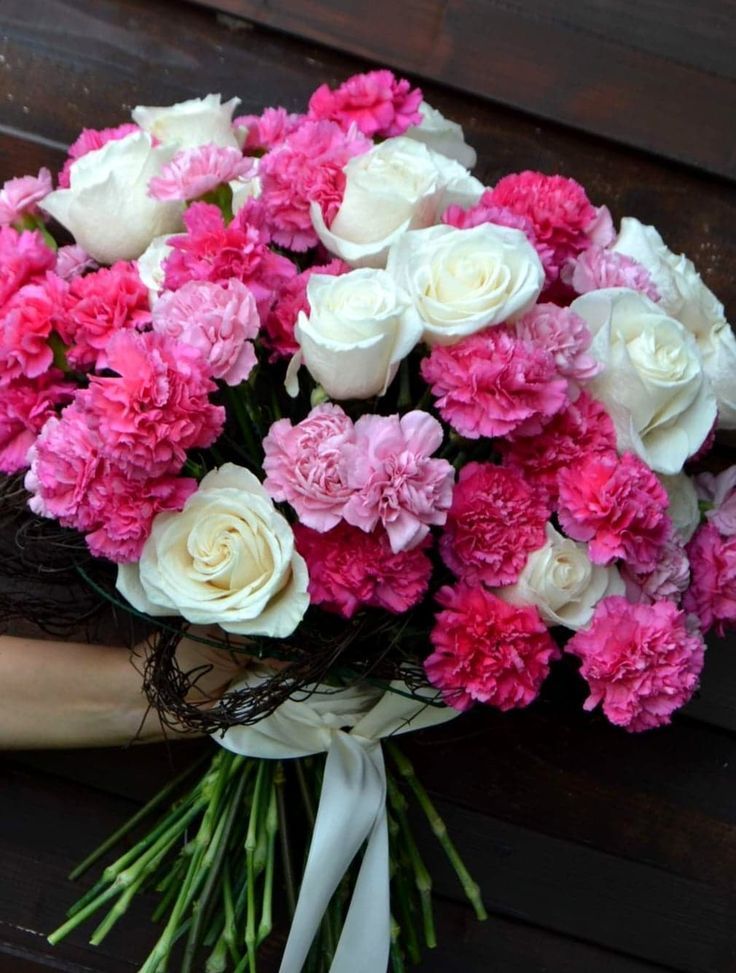 a bouquet of pink and white flowers on a bench