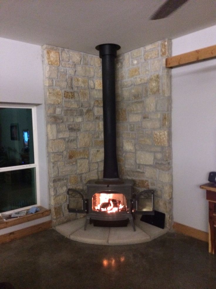 a stone fireplace in a living room next to a window