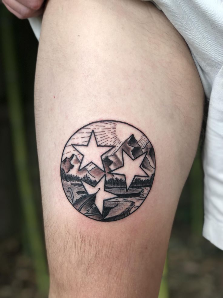 a person with a tattoo on their leg that has three stars in the shape of a circle