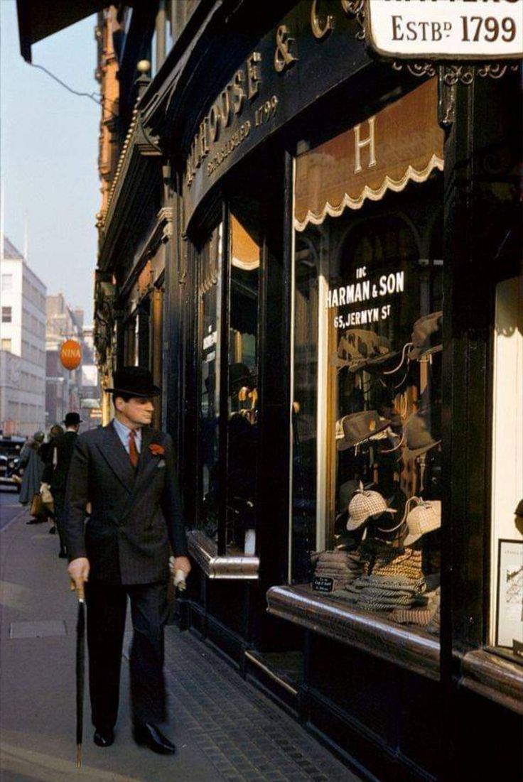 a man in a suit and hat walking down the street