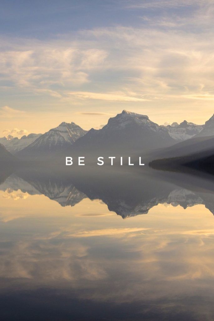 the words be still are displayed in front of a lake with mountains and clouds behind it