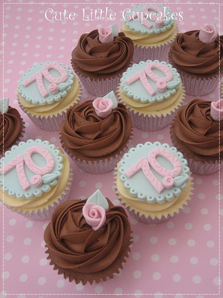 cupcakes with chocolate frosting and pink icing are arranged on a table