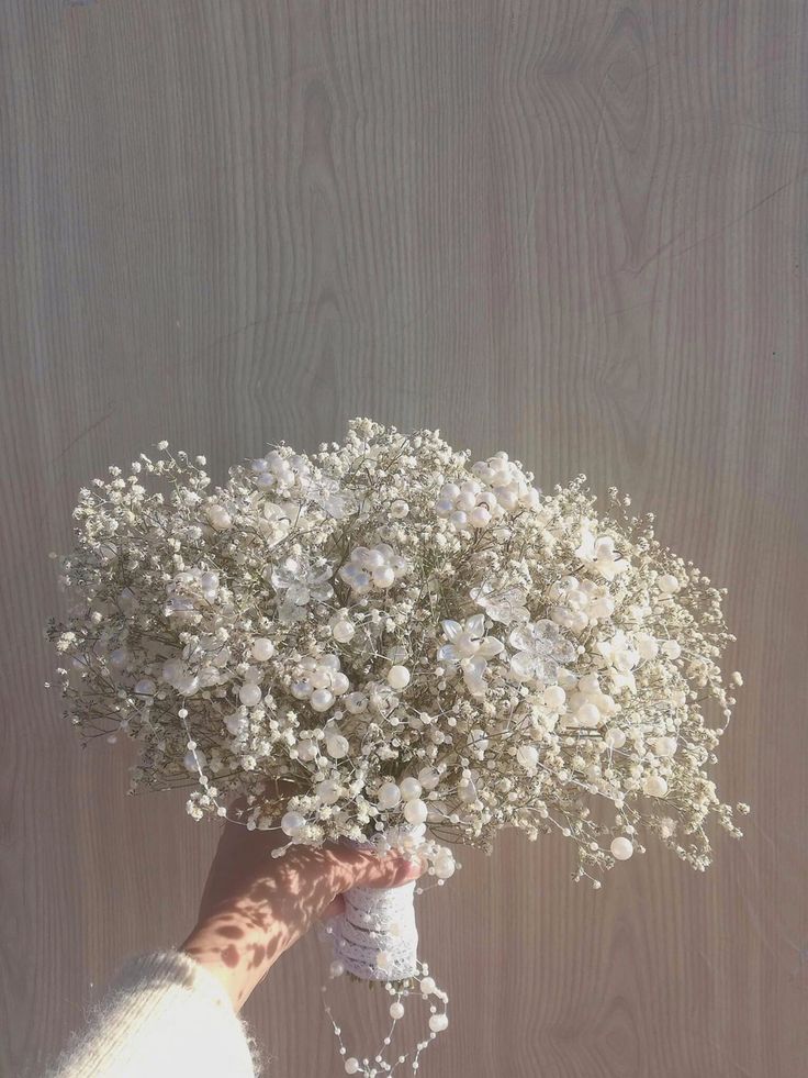 a person's hand holding a bouquet of white flowers