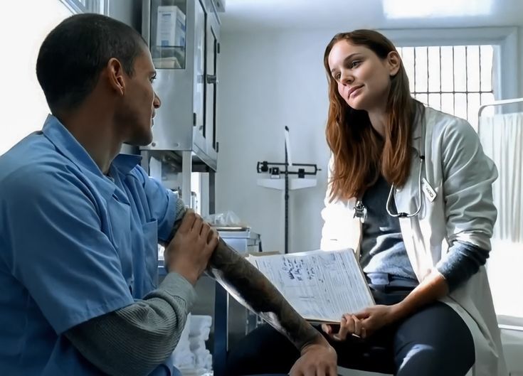 a man sitting on a chair next to a woman who is holding something in her hand