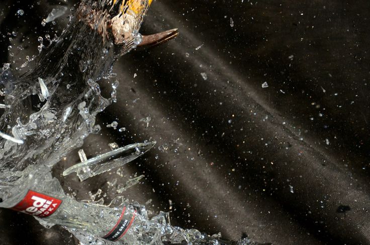 a broken glass bottle with water splashing on it