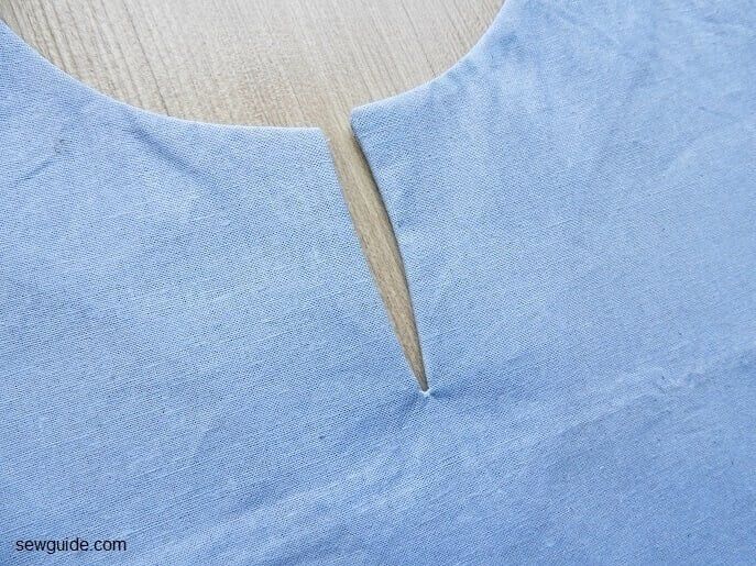 the back of a blue shirt with a piece of fabric cut out to make it easier to sew