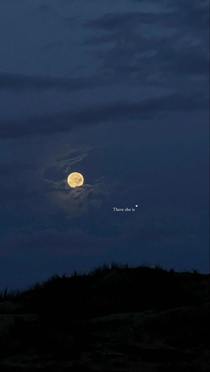 the moon is shining brightly in the night sky over a hill with trees on it