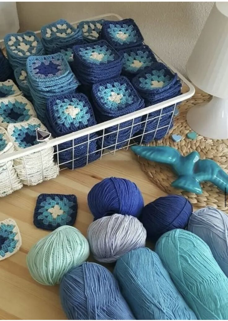 several balls of yarn sitting on top of a wooden floor next to baskets with crocheted items