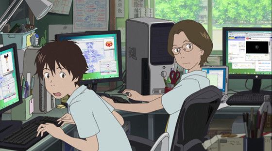 two people sitting in front of computer monitors