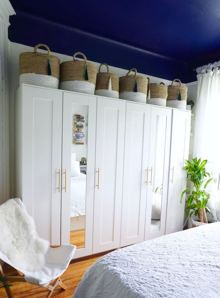 a bedroom with white cabinets and baskets on the wall