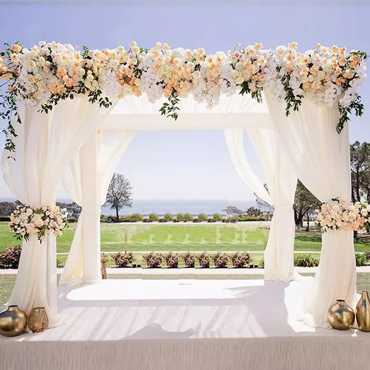 an outdoor wedding setup with white drapes and flowers