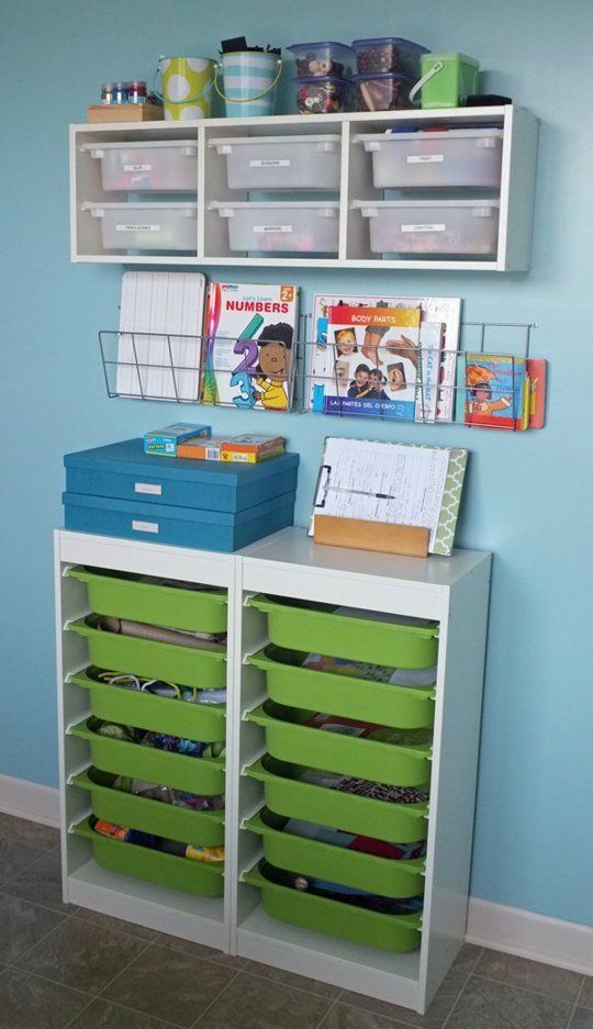 a room with blue walls and green bins on the wall, along with various toy storage containers